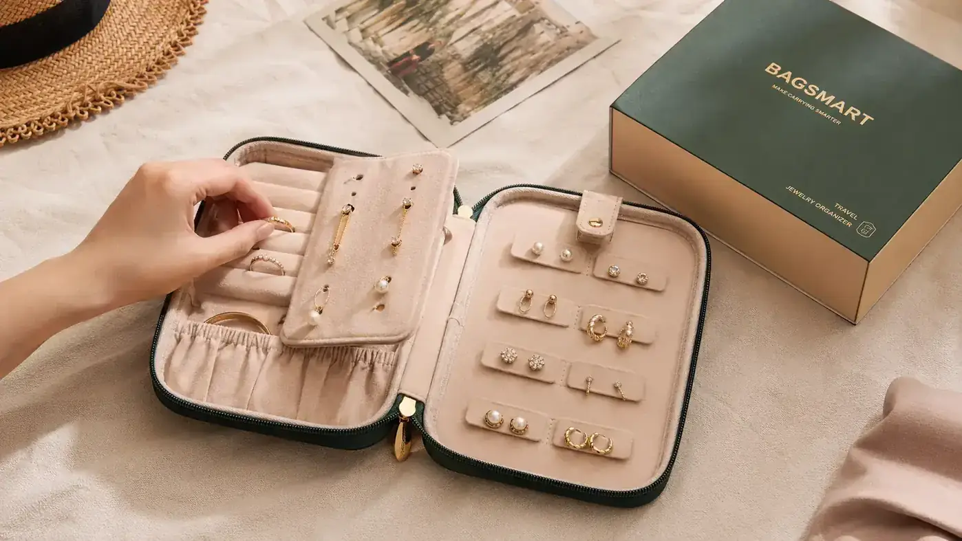 Hand laying a delicate gold necklace into a dedicated necklace slot inside a travel jewelry organizer