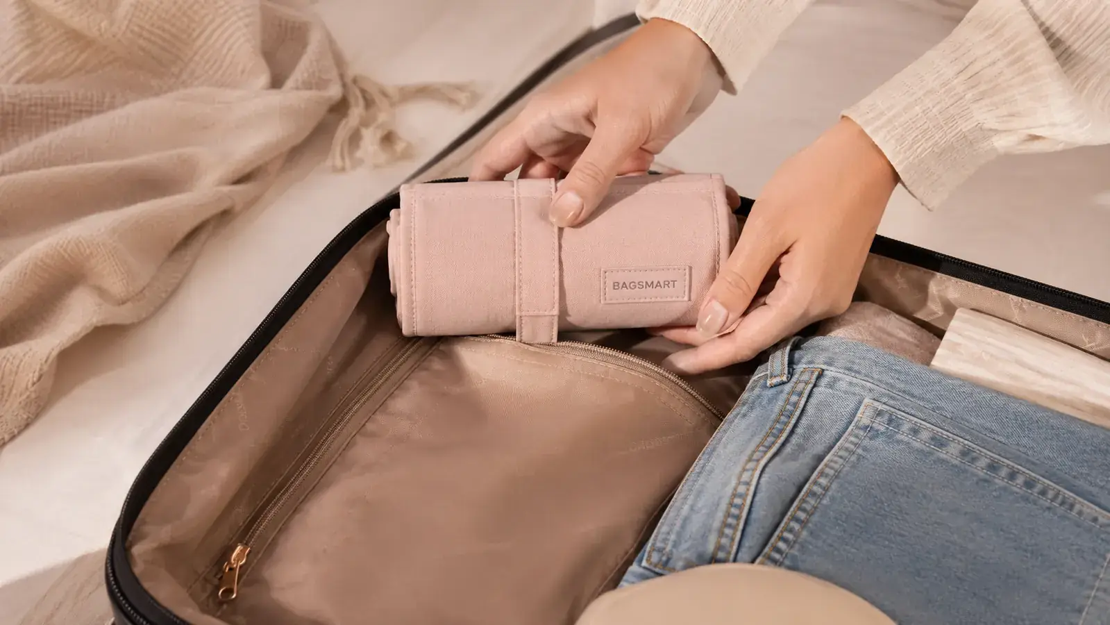 Compact travel jewelry organizer folded shut and sitting inside an open carry-on suitcase