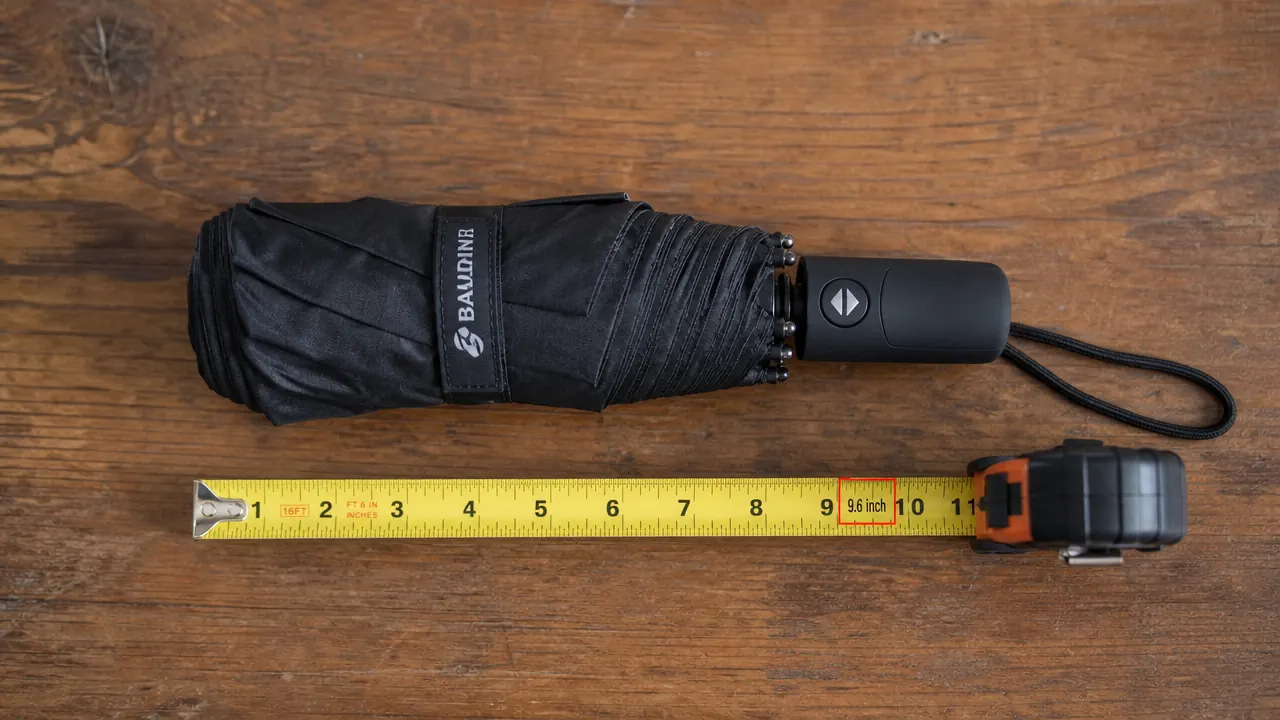 Traveler sliding a compact folded umbrella into the side pocket of a carry-on bag in an airport corridor
